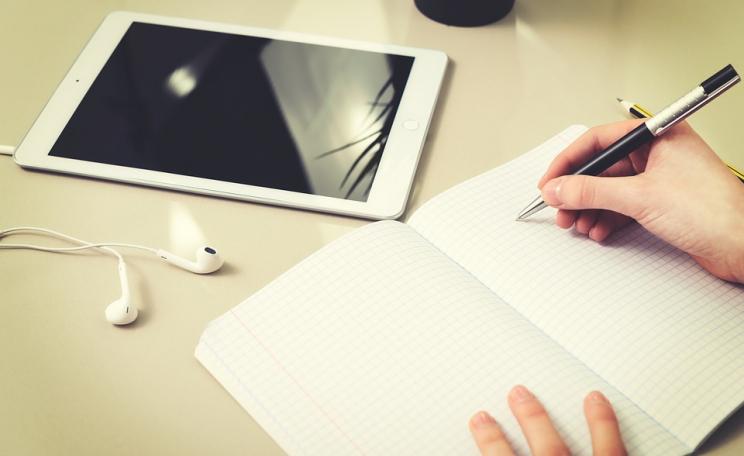 Writer at a desk with notepad, headphones and tablet