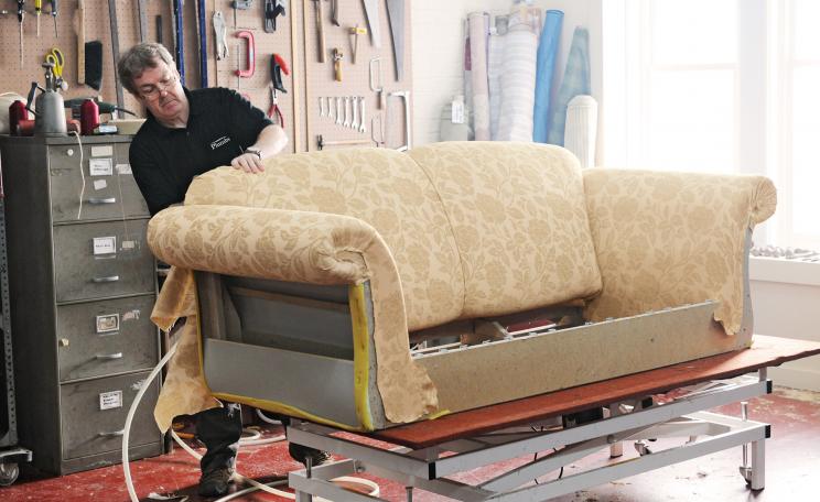 Craftsperson upholstering a sofa