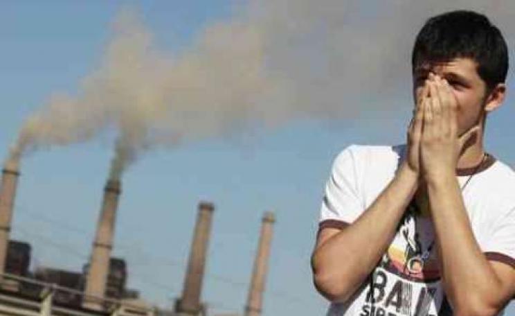 A clean energy campaigner shields his face in front of the Kosovo B coal power station, which is doing much to destroy the small nation's health. Photo: Sierra Club.