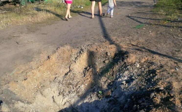 Family walking past a blast crater in Kandrashevka, where 9 civilians died during an aerial attack by alleged Ukranian forces on July 2, 2014. ©2014 Human Rights Watch.