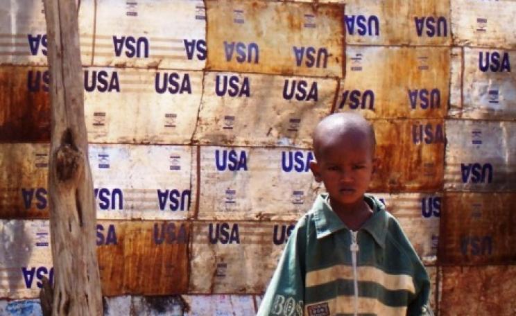 A child leans against a wall made of USAID food aid containers in the flood-destroyed area of Bahere Tsege in Dire Dawa, Ethiopia. Photo: Liz Lucas / Oxfam America.