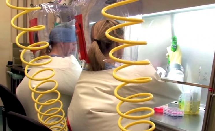 Scientists working inside positive pressure personnel suit at biosafety level 4 (BSL-4) laboratory of the NIAID Integrated Research Facility (IRF) in Frederick, Maryland. Photo: National Institute of Allergy and Infectious Diseases / Public Domain.