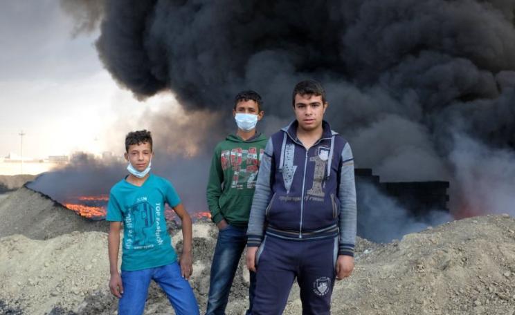 Children near an oil fire at Qayyarah, where ISIS blew up 16 well heads, 26th October 2016. Photo: Benedetta Argentieri / Oxfam.