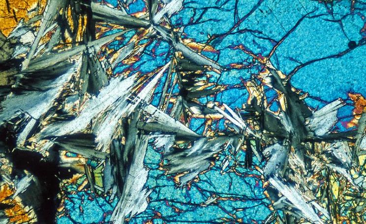An example of the magic CO2-absorbing 'ultramafic' rock that could save the world: Forsterite - Serpentine rock in thin section, magnified under polarized light. Photo: Richard Droker via Flickr (CC BY-NC-ND).