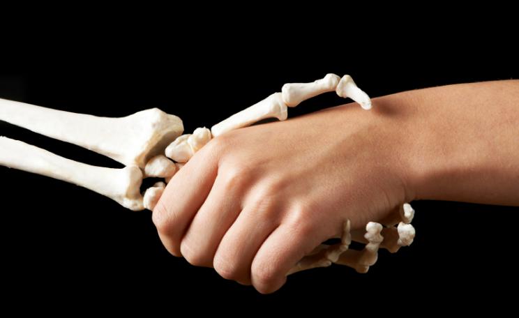 A skeletal hand shakes a fleshly one...