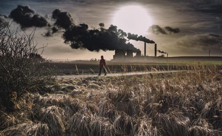 Man walking with factory in background 